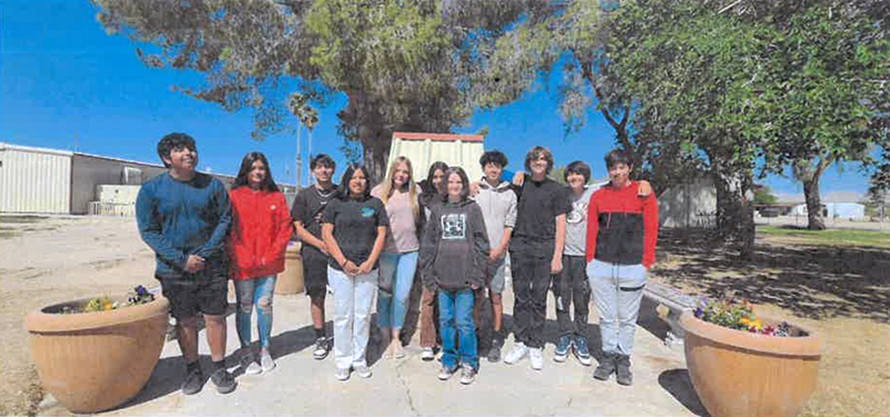 8th grade graduates posing for a picture outside
