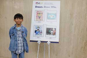 Kharliel standing next to an art board with his art on it